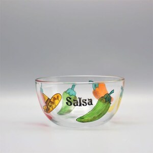 May include: A clear glass salsa bowl with a painted design of green, red, and yellow peppers. The bowl has the word "Salsa" painted on the front.