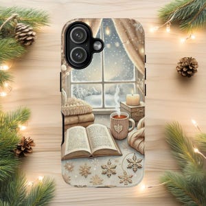 May include: A phone case featuring a cozy winter scene. The design includes a window overlooking a snowy landscape, a stack of books, a mug of tea, and a lit candle. Decorative snowflakes and pine branches add to the seasonal theme.