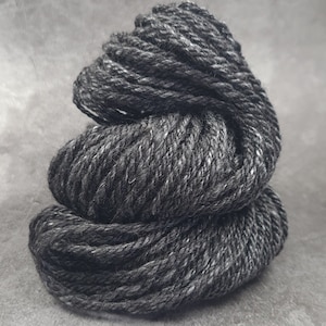May include: A skein of dark gray yarn with a subtle fleck of white.