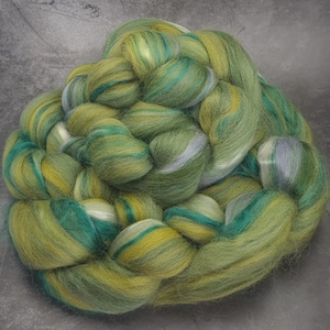 May include: A bundle of green, yellow, and blue hand-dyed merino wool roving. The roving is arranged in a braided pattern.