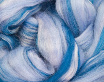 May include: A close-up of a bundle of blue and white wool roving. The roving is soft and fluffy, and the colors are blended together in a swirling pattern.