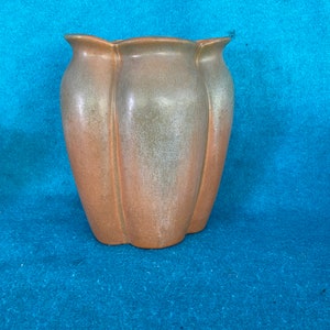 May include: A brown and green ceramic vase with a fluted design. The vase has a rounded bottom and a wide opening.