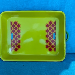 May include: A yellow baking dish with a blue rim and green handles. The dish has a red and yellow geometric pattern with the text "Peter Max" on each side.