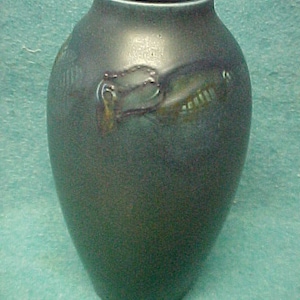 May include: A dark green ceramic vase with a stylized floral design in shades of brown and gold.