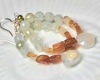 May include: A pair of handcrafted earrings featuring a combination of faceted, round, and rectangular beads in shades of white, yellow, and orange. The earrings have silver-colored ear wires and gold-colored accents.