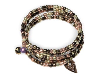 May include: A multi-strand wrap bracelet composed of small metallic beads in shades of bronze, copper, and silver. The bracelet features a dangling faceted dark bead, a smooth purple bead, and a small heart-shaped charm with a textured surface.