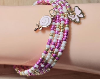 May include: A beaded wrap bracelet with pink, white, and gold beads. The bracelet features a pink butterfly charm and a pink lollipop charm. The bracelet is wrapped around a wrist.