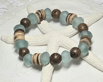 May include: A beaded bracelet featuring alternating light blue, brown, and tan beads. The bracelet is made of round, smooth beads and is displayed on a white starfish. The brown beads have a wood grain pattern.