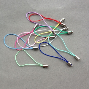 Puede incluir: Surtido de llaveros de teléfono de cuerda de colores con cierres de metal plateado. Los llaveros son de varios colores, incluyendo rojo, rosa, azul, verde, amarillo y blanco.