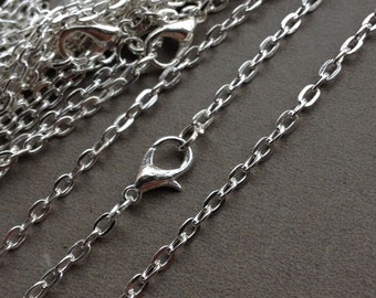 May include: A close-up of multiple silver chains with lobster clasps. The chains are arranged in a pile, with some of them extending out to the side.