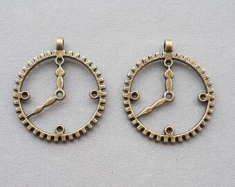 May include: Two antique gold-toned metal clock face charms with a gear design around the edge. Each charm has a loop at the top for hanging.