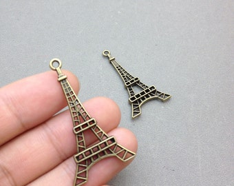 Puede incluir: Dos encantos de la Torre Eiffel de oro antiguo. Los encantos son detallados e intrincados, con un diseño delicado.