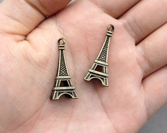 Puede incluir: Dos encantos de la Torre Eiffel de oro antiguo. Los encantos son detallados y tienen un aspecto vintage.