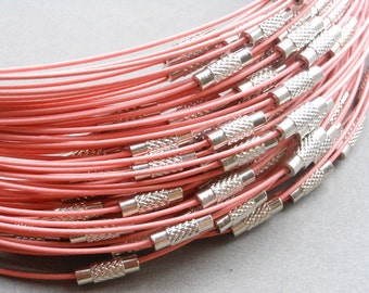 May include: A close-up of a bundle of pink elastic cord with silver metal clasps. The cord is arranged in a spiral pattern, showing the clasps at regular intervals.