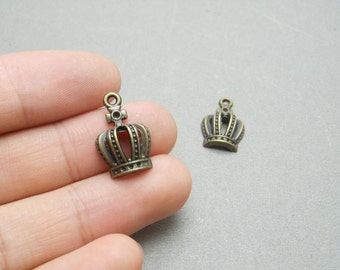 May include: Two antique gold-toned crown charms with a loop at the top for attaching to jewelry or crafts.