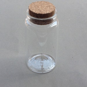 May include: A clear glass bottle with a cork stopper. The bottle is empty and has a textured surface.