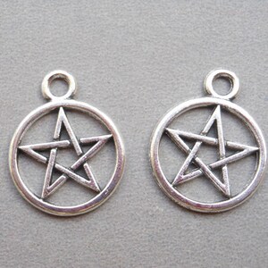 Può includere: Due ciondoli in metallo color argento a forma di cerchio con un pentagramma all'interno.