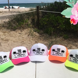 May include: Five trucker hats with white mesh backs and different coloured brims. The hats have a black palm tree graphic and the text "Shake Your Palm Palms!" with a slogan underneath.