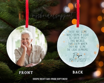 May include: A blue and white Christmas ornament with a gold star design. The ornament features a quote about light and a personalized message that reads "Papa 1941-2023".