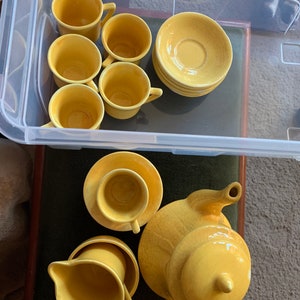 May include: A yellow tea set comprising a teapot, creamer, sugar bowl, cups, and saucers. The set is made of ceramic and has a vintage appearance.