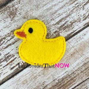 May include: A yellow felt rubber ducky applique with a black eye and an orange beak. The ducky is stitched with a yellow thread.