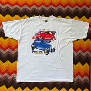 May include: White t-shirt featuring a graphic of two classic hot rods, one red and one blue, with the text "Rod Run" and "Pigeon Forge, Tennessee." The shirt is made of a soft, comfortable material.