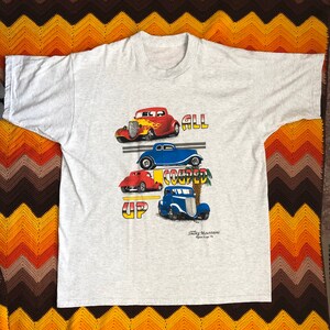 May include: A gray t-shirt with a graphic of four vintage cars and the text "All Couped Up". The cars are red, blue, and gray. The text "Smokey Mountains Pigeon Forge, TN" is at the bottom of the graphic.