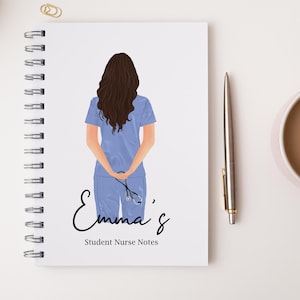 May include: A white spiral-bound notebook featuring a graphic of a person with long brown hair wearing light blue scrubs and holding a stethoscope behind their back. The text reads Emma's Student Nurse Notes in black script and serif font.