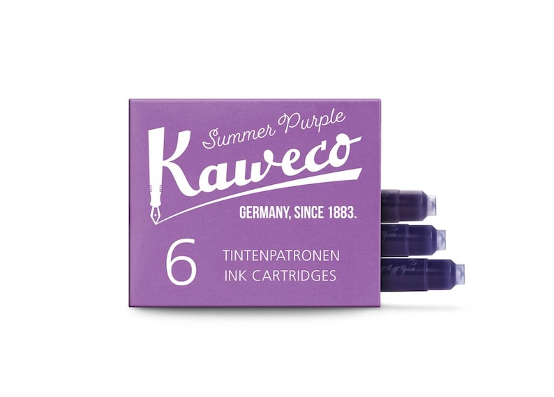 Pu&ograve; includere: Una scatola viola di cartucce d'inchiostro Kaweco Summer Purple. La scatola ha un testo bianco che recita "Summer Purple Kaweco Germany, Since 1883" e "6 Ink Cartridges". Sono visibili tre cartucce d'inchiostro viola.