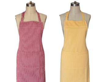 May include: Two aprons on mannequins. One is red and white striped, the other is yellow and white striped. Both aprons have a bib, a pocket, and adjustable neck straps. The aprons are made of a lightweight fabric.