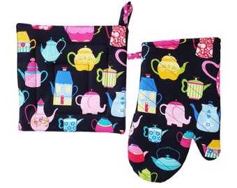 May include: A black pot holder and oven mitt set. The set features a colorful teapot pattern in pink, blue, yellow, and green. The pot holder is square with a hanging loop, and the oven mitt has a loop for hanging.
