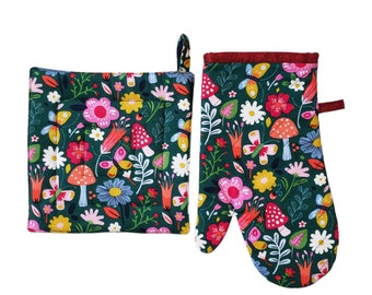 May include: A dark green oven mitt and pot holder set with a colorful floral and mushroom pattern. The design includes pink, white, and yellow flowers, butterflies, and red mushrooms. The pot holder has a hanging loop.