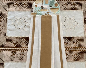 May include: A kitchen-themed hanging towel with a striped design. The top portion features a pattern of kitchen utensils, mugs, and bowls on a light blue and beige background. The towel has alternating vertical stripes of white and tan.