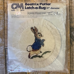 May include: A Beatrix Potter Latch-a-Rug kit in a plastic package, featuring a 27-inch diameter circular rug design of Peter Rabbit in a blue jacket. The packaging includes the text Beatrix Potter Latch-a-Rug and Erica Wilson signature.