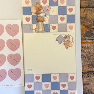 May include: A stationery set featuring a cream-colored letter sheet with a blue and cream checkered border, pink hearts, and illustrations of brown mice sewing. Includes a matching sheet of pink heart-shaped stickers with the text Stamp.