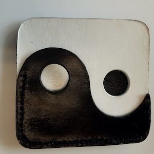 Könnte beinhalten: Eine schwarze und weiße Ledergeldbörse mit einem Yin-Yang-Symbol.