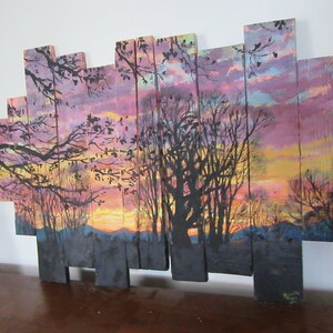 May include: A sunset scene painted on wooden planks, with a silhouette of trees in the foreground and a colorful sky in the background.