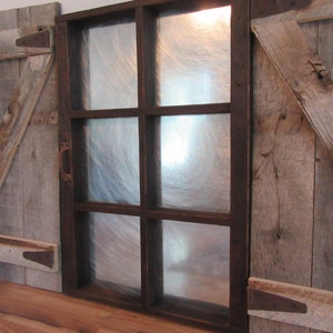 May include: A rustic wooden door with a window pane made of frosted glass. The door is made of reclaimed wood and has a distressed look. The window pane is divided into four sections by dark brown wooden frames.