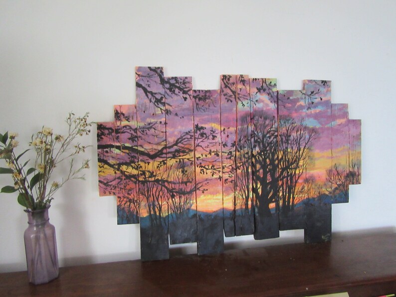May include: A sunset scene painted on wooden planks, with a silhouette of trees and a colorful sky. The planks are arranged in a staggered pattern to create a unique and modern look.