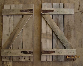 May include: Two rustic wooden shutters with diagonal bracing and rusty metal hinges. The shutters are made of weathered wood planks and have a distressed look. The date 02/12/2015 is written on the bottom right shutter.