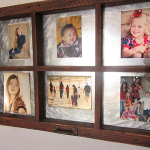 May include: A rustic wooden picture frame with a metal backing holds eight photos. The frame has a distressed wood finish and a metal handle. The photos are of various sizes and show different people and scenes.