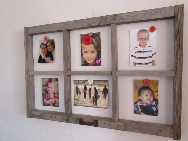 May include: A rustic, wooden picture frame with six openings, each holding a photograph. The frame is made of weathered gray wood and has a grid-like design. Photos are secured with decorative buttons. The photos feature people of different ages.