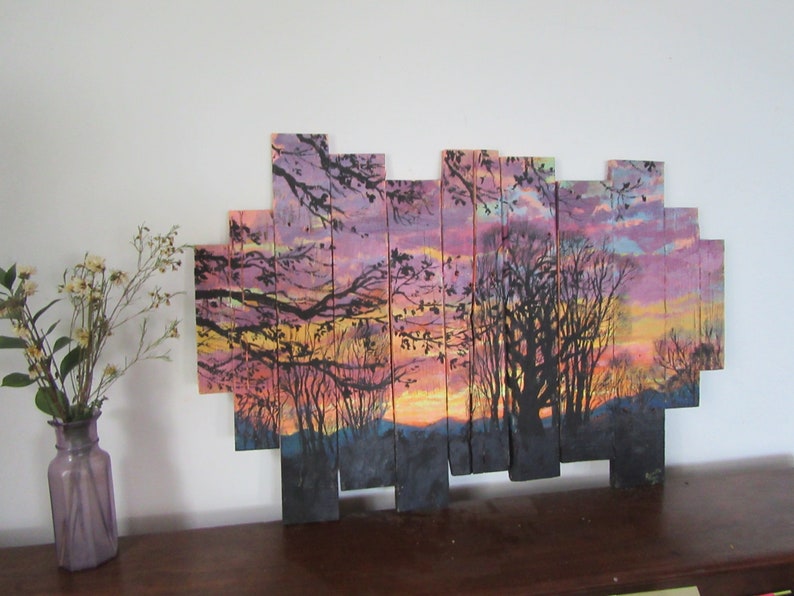May include: A sunset scene painted on wooden planks, with a silhouette of trees and a colorful sky. The planks are arranged in a staggered pattern to create a unique and modern look.