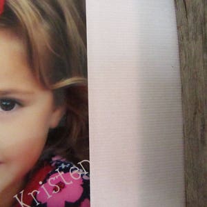 May include: A portrait of a young girl with blonde hair and a red bow. The girl is wearing a pink and black floral top. The name "Kristen" is printed in a cursive font on the bottom of the image.