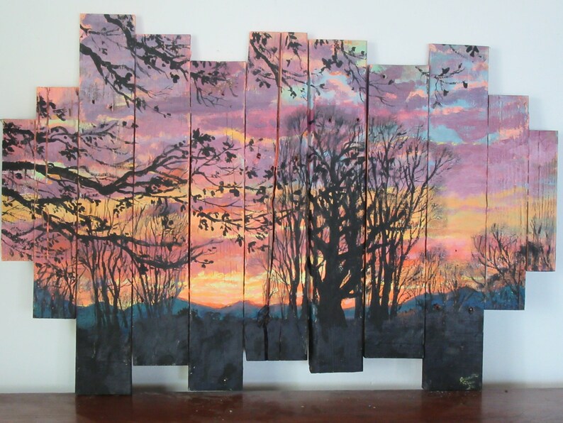 May include: A sunset scene painted on wooden planks. The painting features a silhouette of trees against a pink, orange, and yellow sky. The planks are arranged in a staggered pattern.