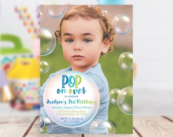 May include: A birthday invitation with a photo of a young boy in front of a green background with colorful bubbles. The text reads "POP on over to celebrate Jackson's 3rd Birthday. Saturday, August 27th at 2:00 pm. 123 Your Address Here. Your City Here, ST 01234. RSVP to Nicole at 555-123-4567."