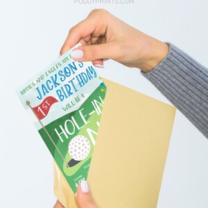 May include: A golf-themed birthday invitation with a green and blue colour scheme. The invitation features a golf ball, a golf flag, and the text "Birdies and Eagles are for Jacksons 1st Birthday Will be a Hole-in-One".