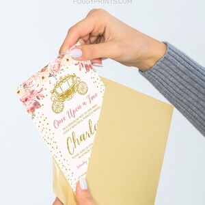 Op de afbeelding: Een witte uitnodiging met gouden glitter en roze bloemenaccenten. De uitnodiging luidt "Er was eens" en bevat de naam "Charlotte".