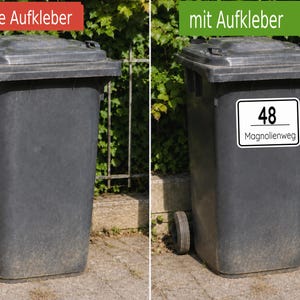 May include: Two dark gray plastic waste bins with wheels. The left bin is plain, while the right bin features a white rectangular sticker with rounded corners displaying the number 48 and the text Magnolienweg in black lettering.