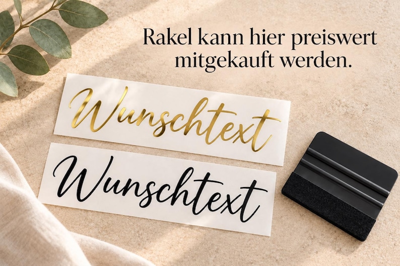 May include: Two rectangular adhesive labels with the German word "Wunschtext" in a cursive script font. One label features metallic gold lettering, while the other has black lettering. A black plastic squeegee tool is positioned to the right.